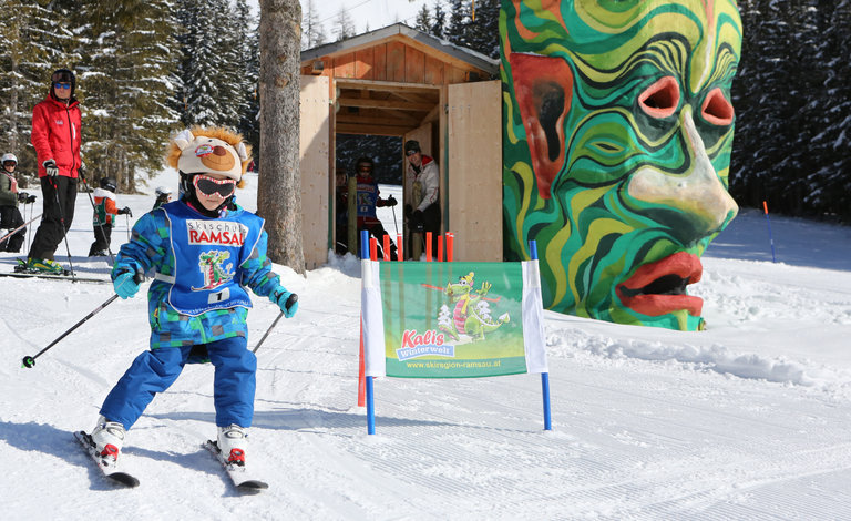 Kind am Skifahren mit kunstvollem Steinkopf im Hintergrund. | © Hans-Peter Steiner