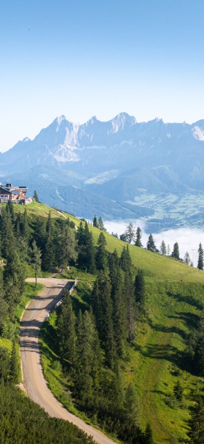 Green Hochwurzen summit backdrop with hut, mountain road and view of the Enns Valley and the Dachstein massif | © Josh Absenger