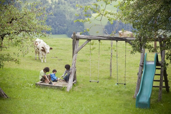 Moserhof - spielende Kinder mit Kühen und Schaukel